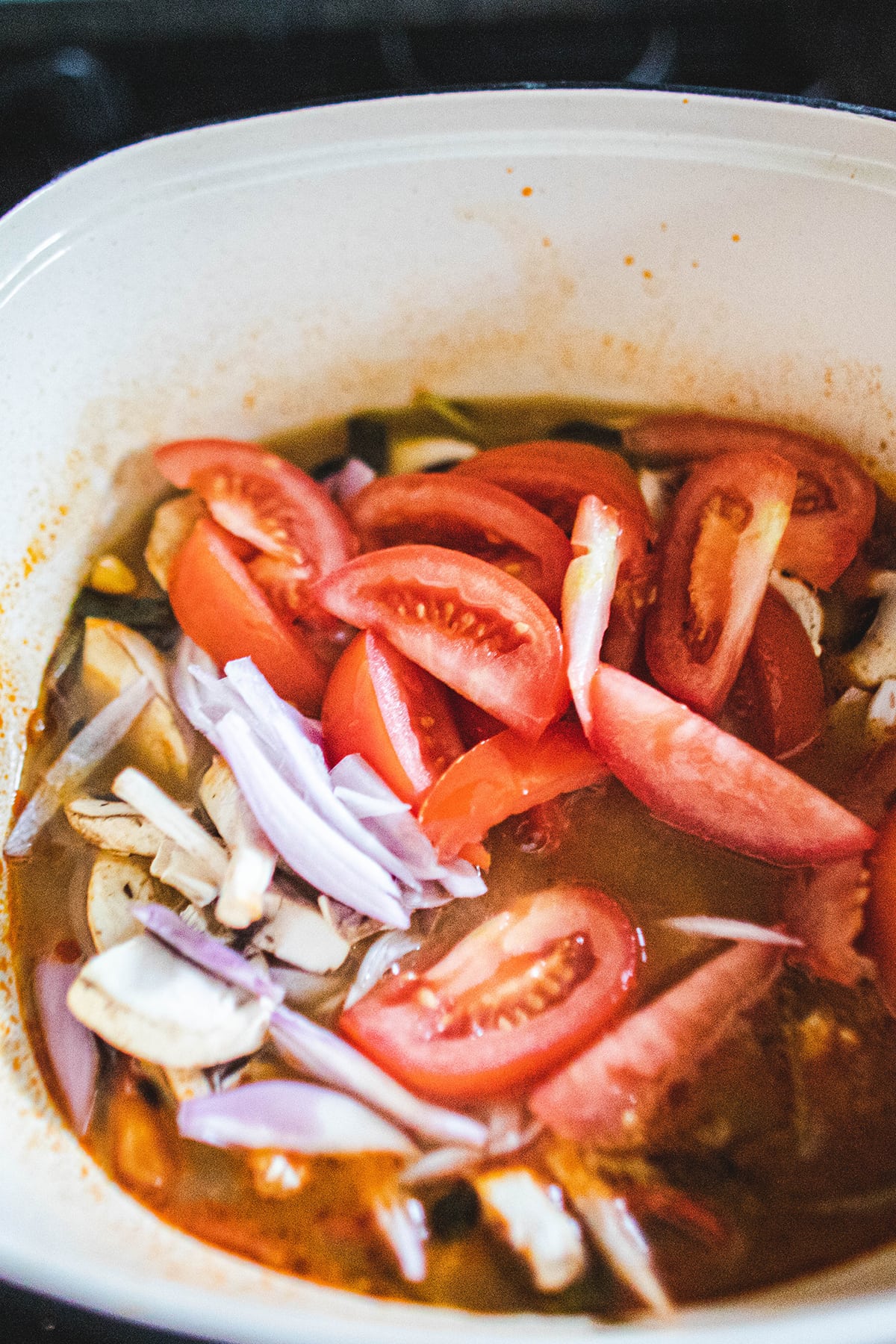 tomato, mushroom and shallot added to tom yum broth 