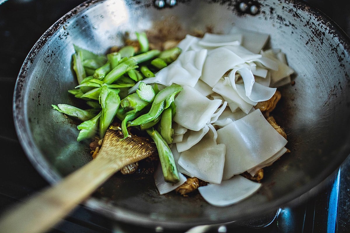 Chinese broccoli stems and pad see ew noodles in a wok.