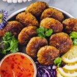 Thai shrimp cakes with a side of sauce and lemon wedges.