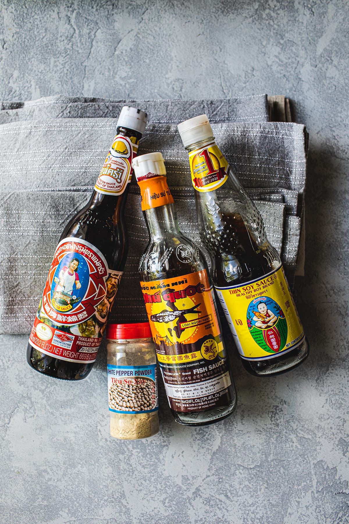 bottles of fish sauce, soy sauce, oyster sauce and ground white pepper 