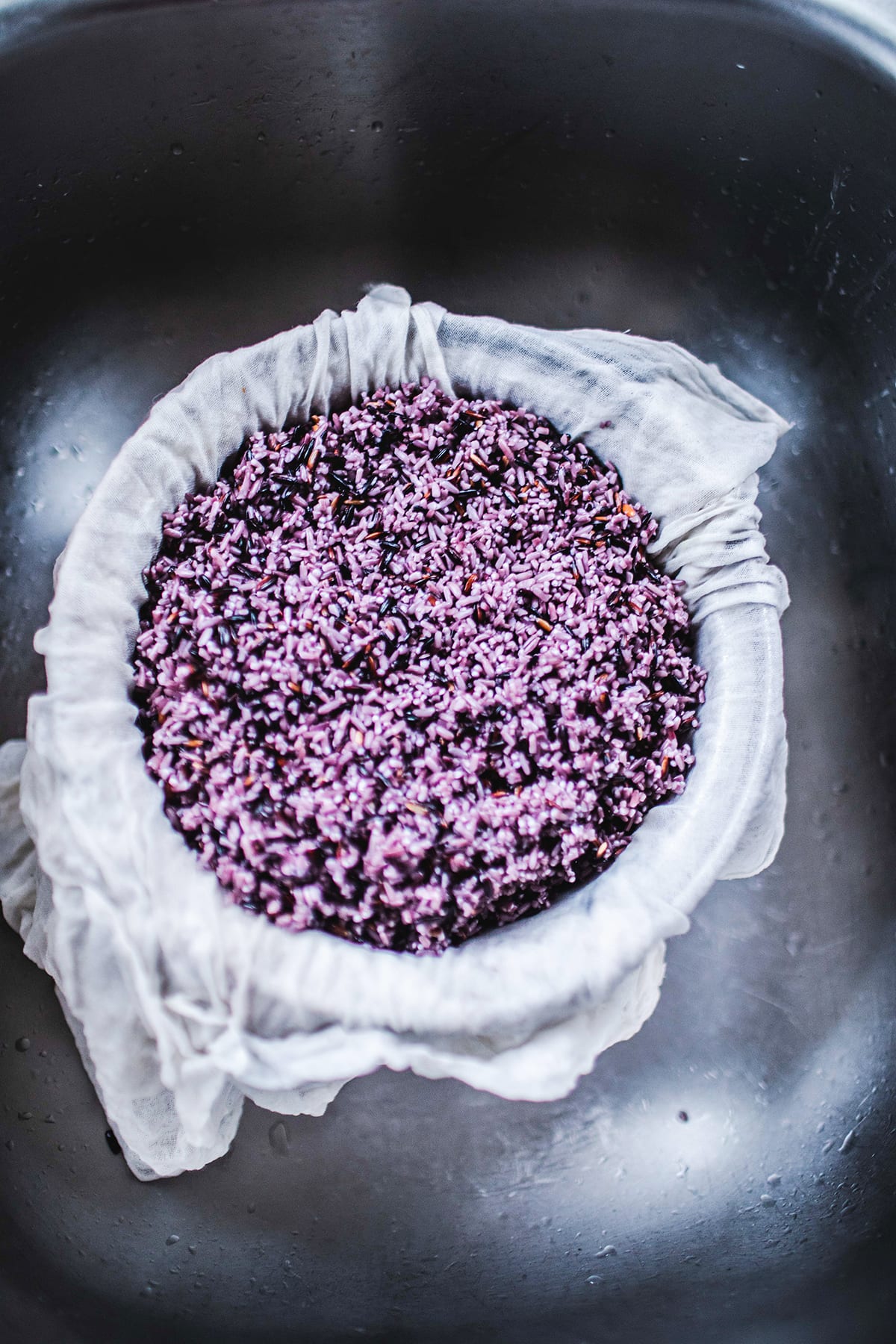 Purple sticky rice in a bowl in a sink.