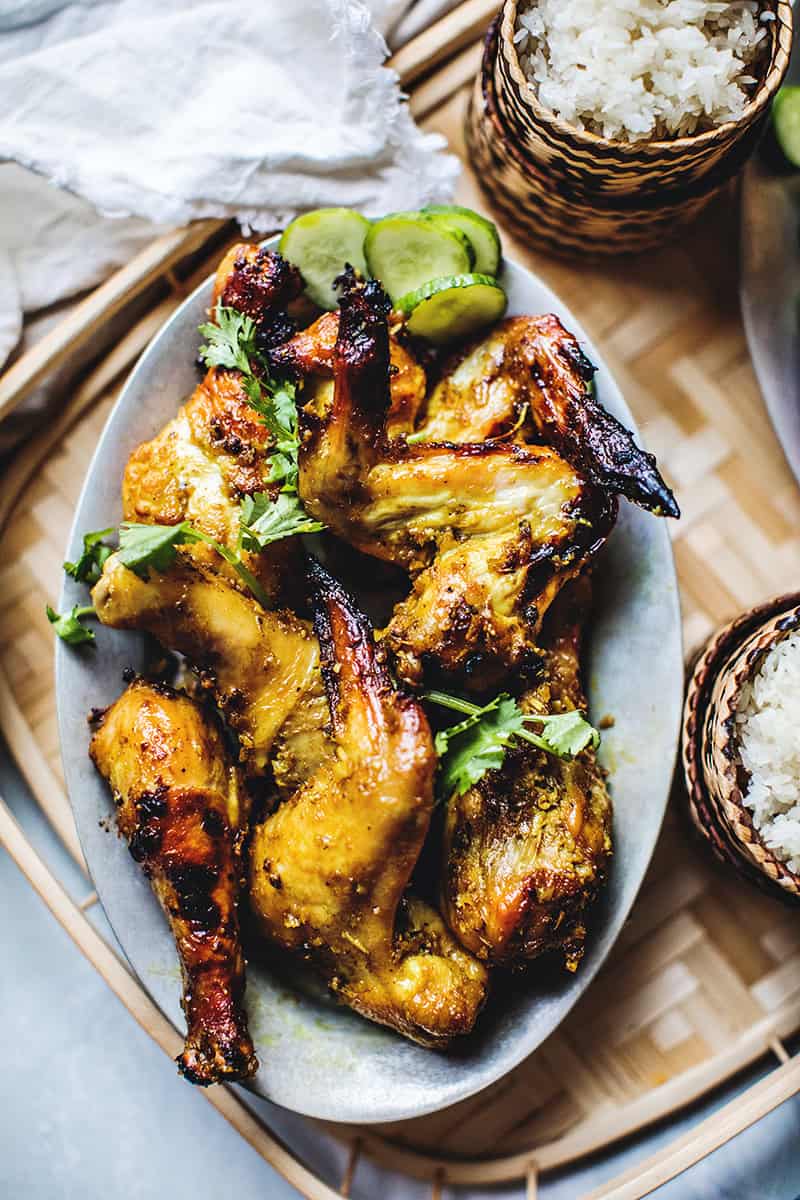 Gai yang chicken wings on a tray with rice. 