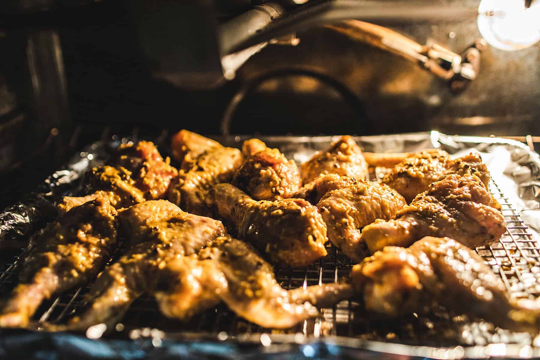 Gai yang chicken wings on baking rack in oven. 