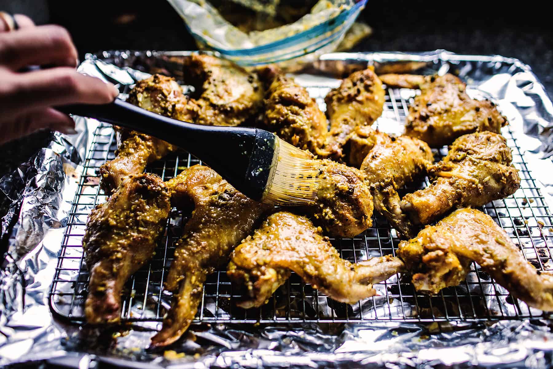 brushing Gai yang chicken wings on baking rack.