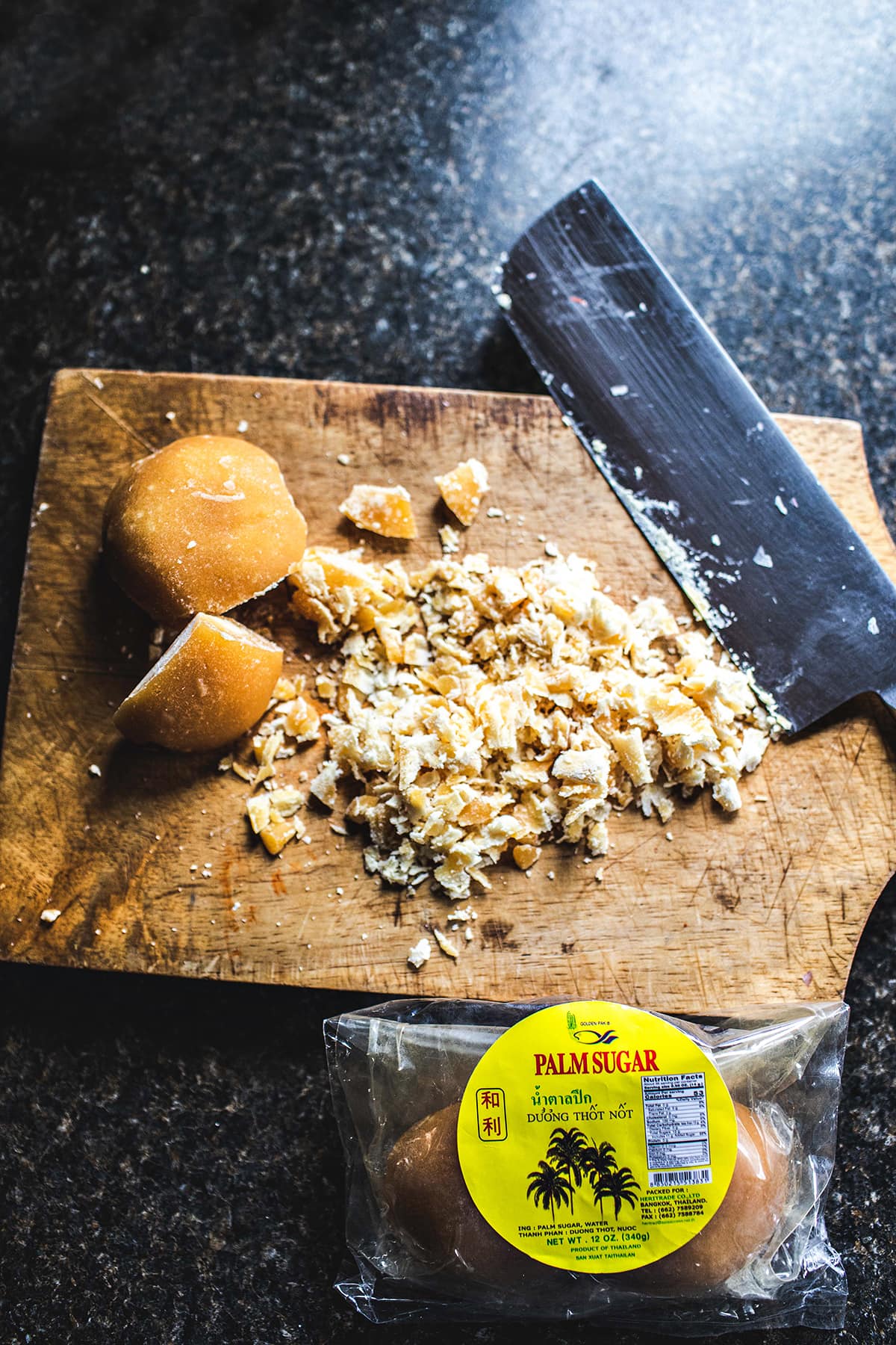 shaved palm sugar with a knife on a cutting board.