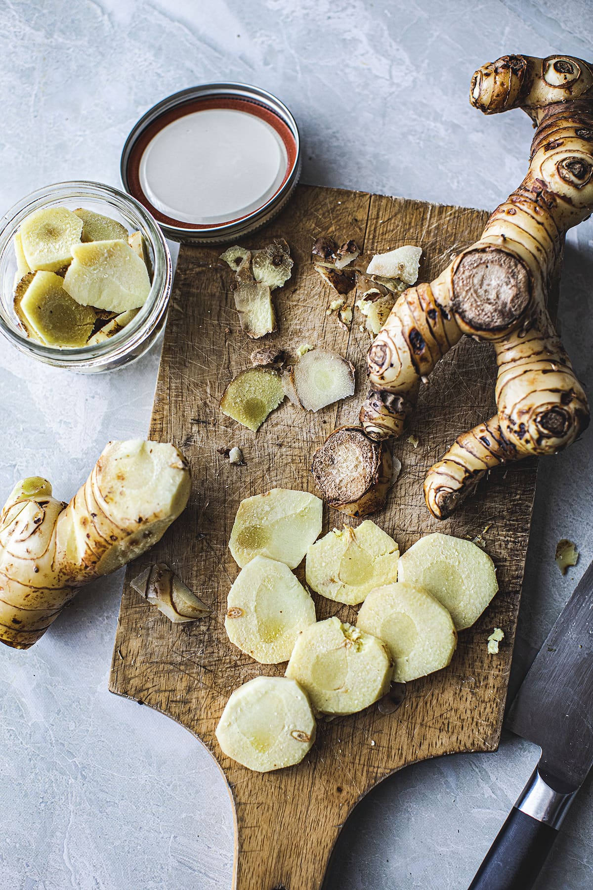 Fresh Galangal chopped and whole on a cutting board.