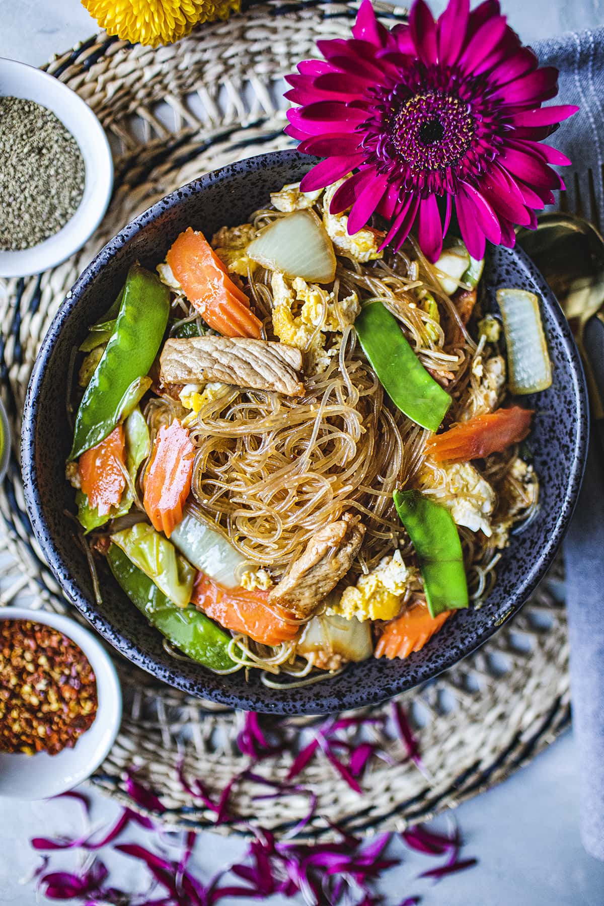 Pad woon sen stir fry noodles in a black bowl.