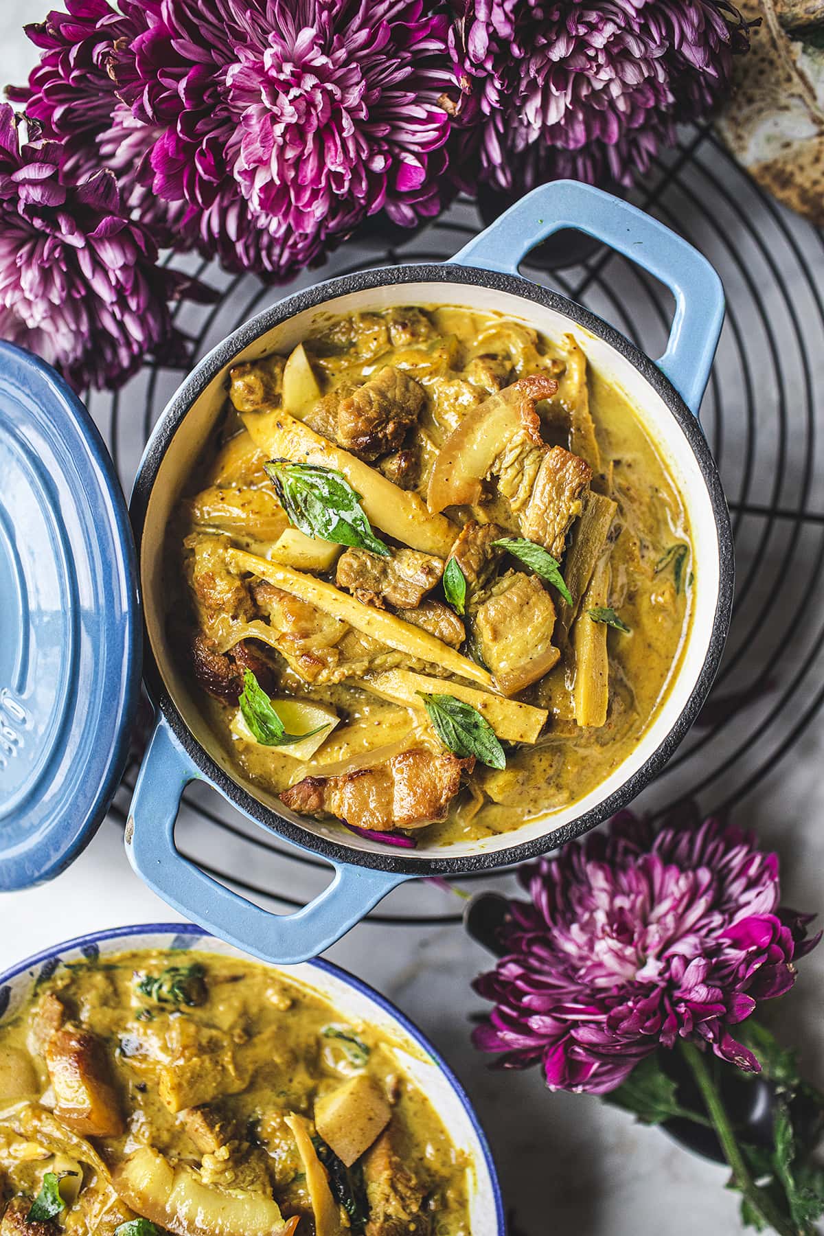 yellow curry in a blue dutch oven on a table with pink flowers