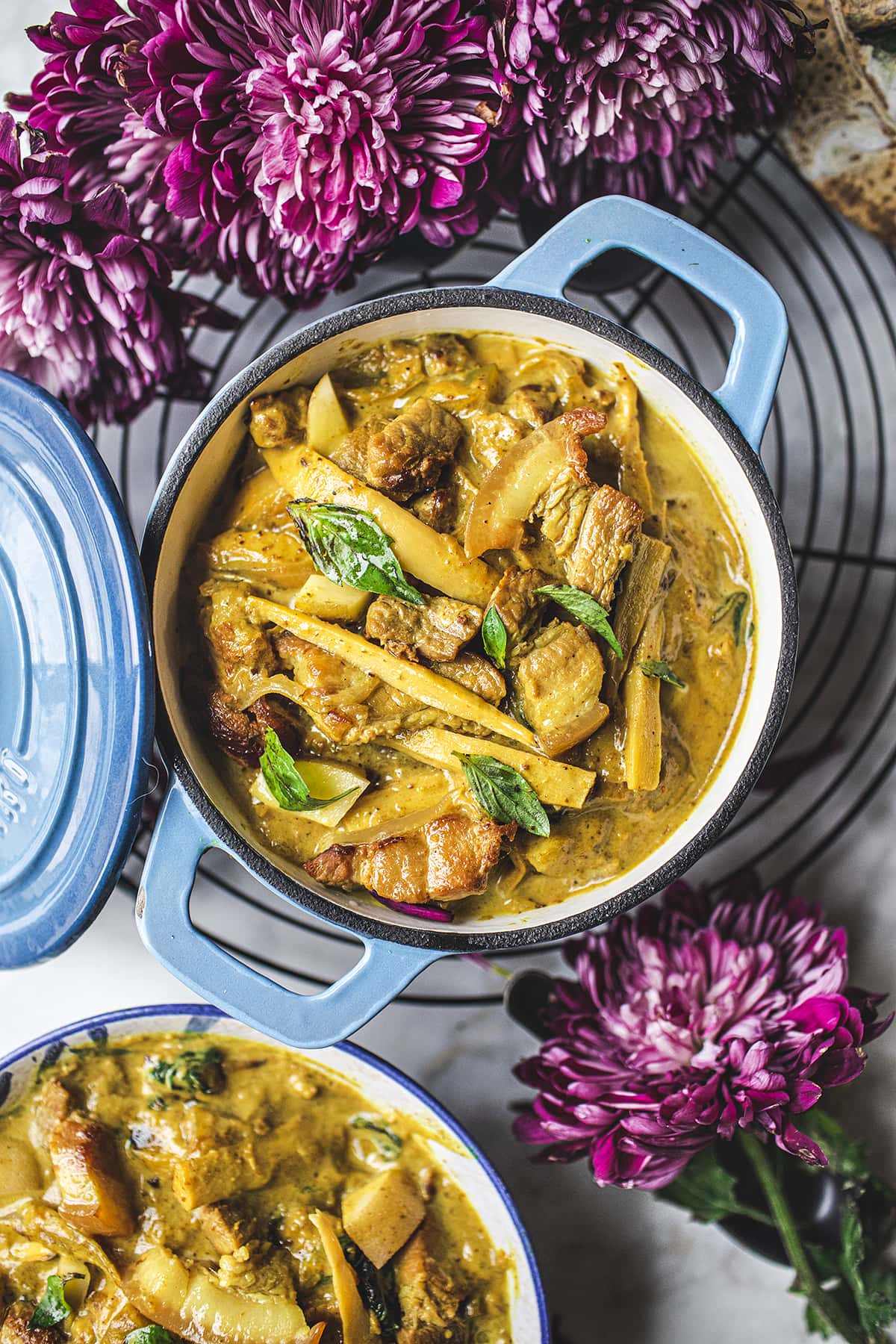 yellow curry in a blue dutch oven on a table with pink flowers