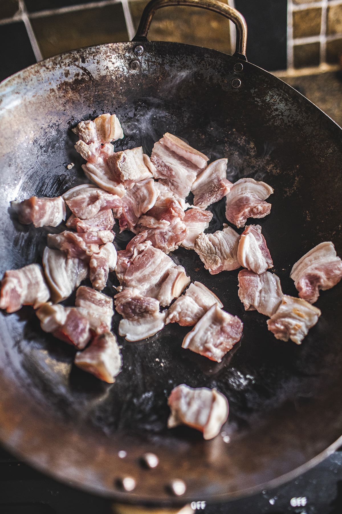 Sliced pork belly frying in a wok.