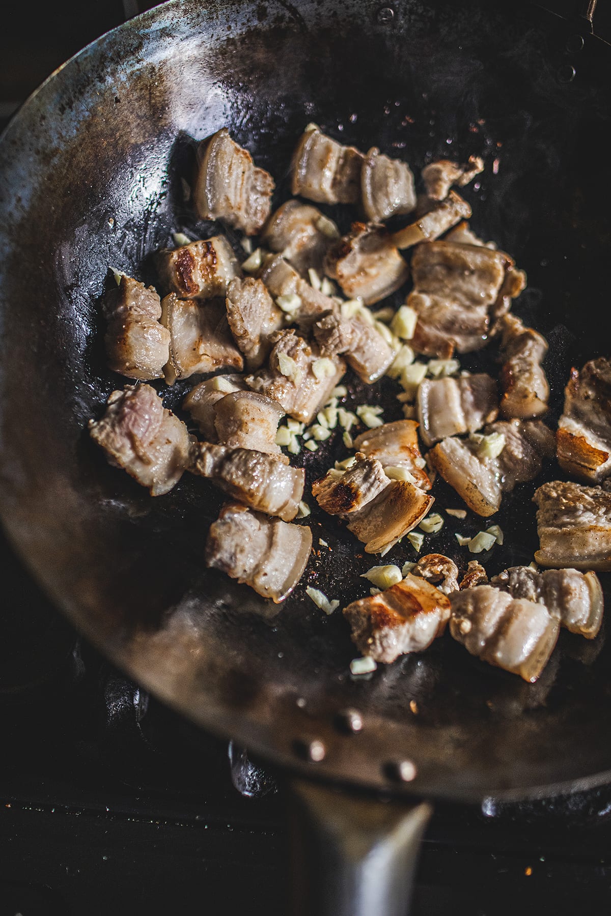 Pork belly frying with garlic in a wok.