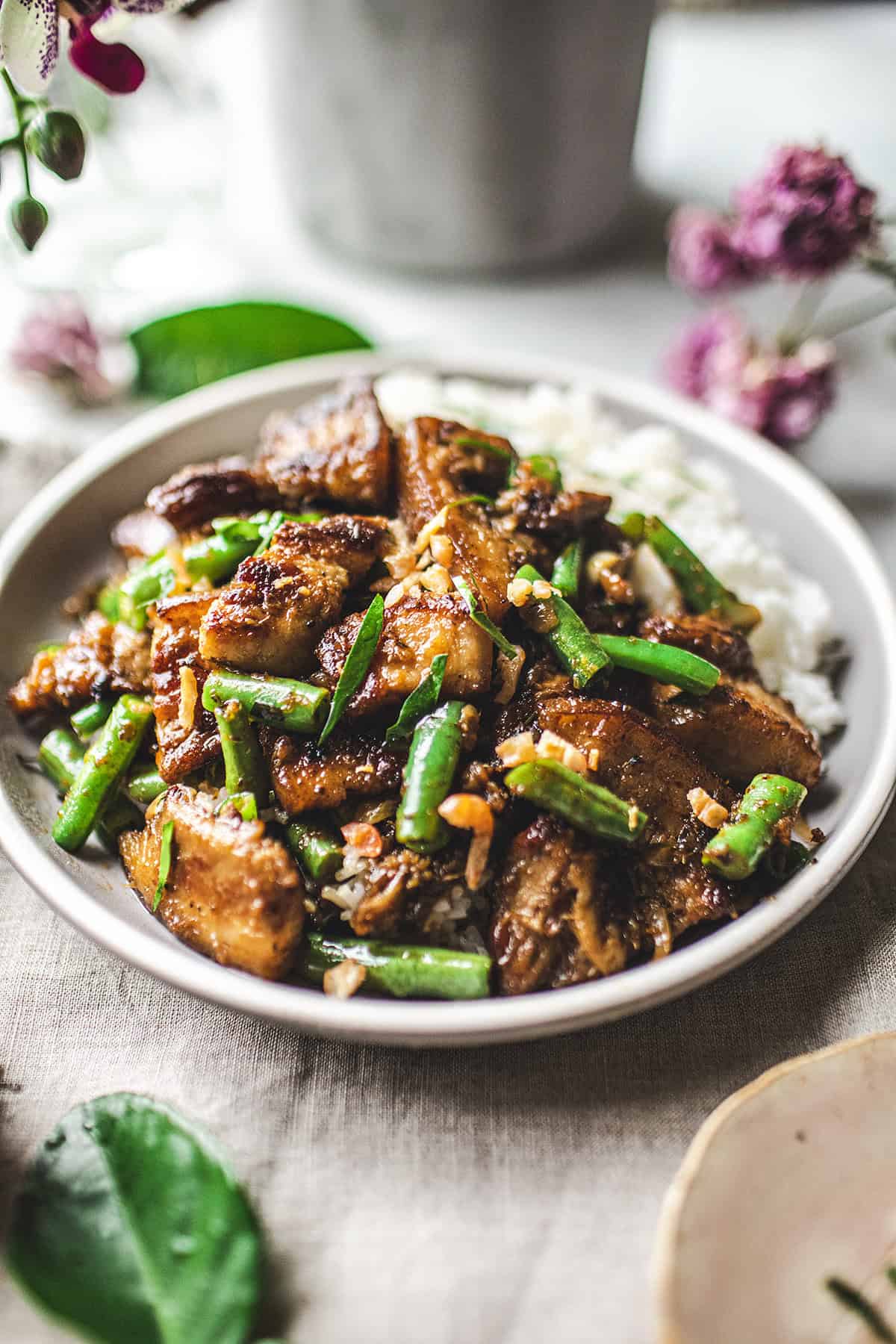 stir fried pork belly over rice in a round plate