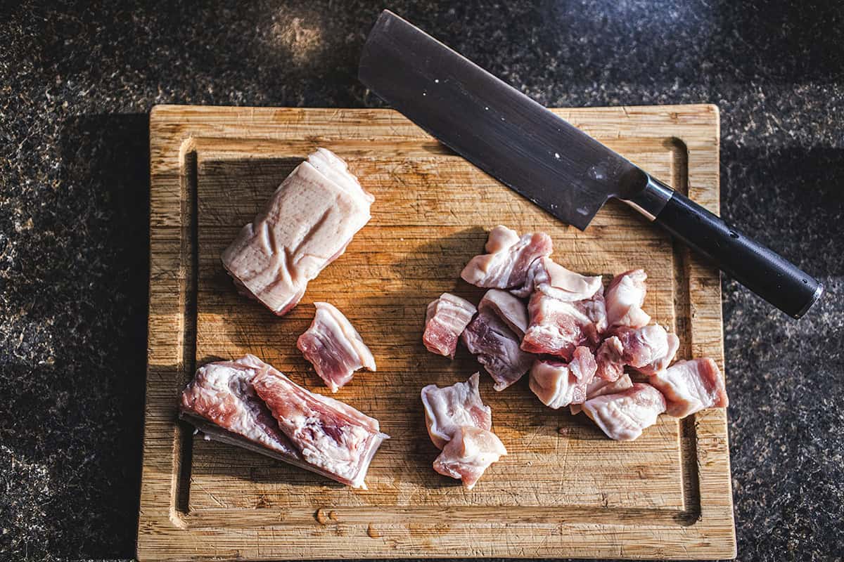 sliced pork belly on a cutting board with a knife