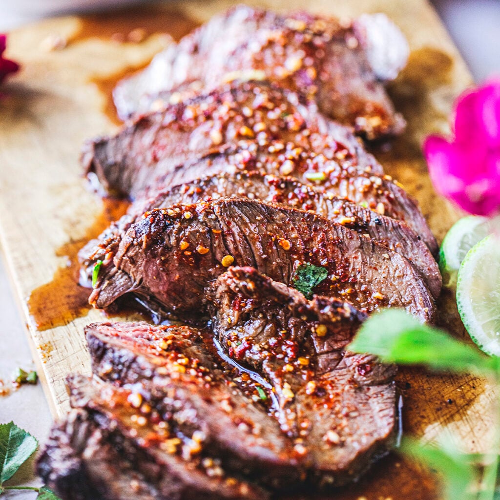 sliced crying beef with chili sauce on top.