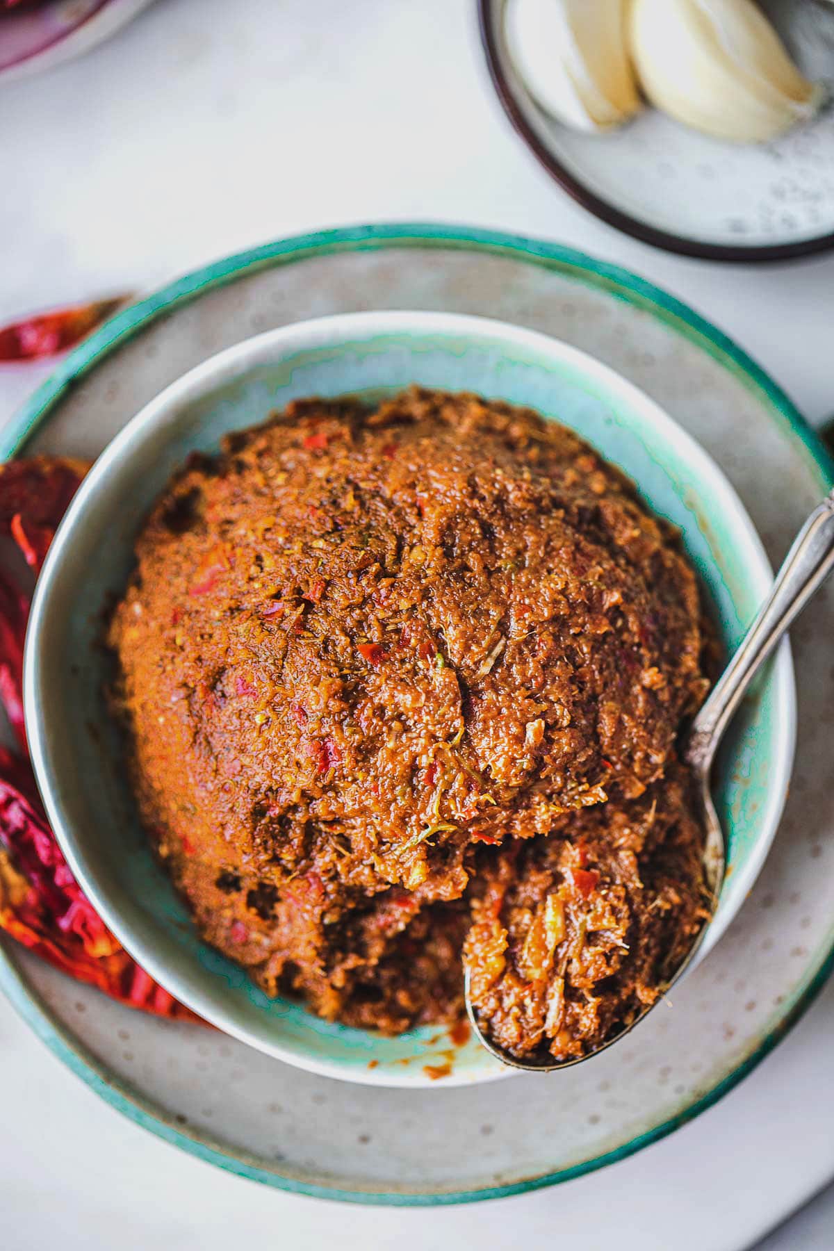 A spoon scooping prik king curry paste from a bowl.