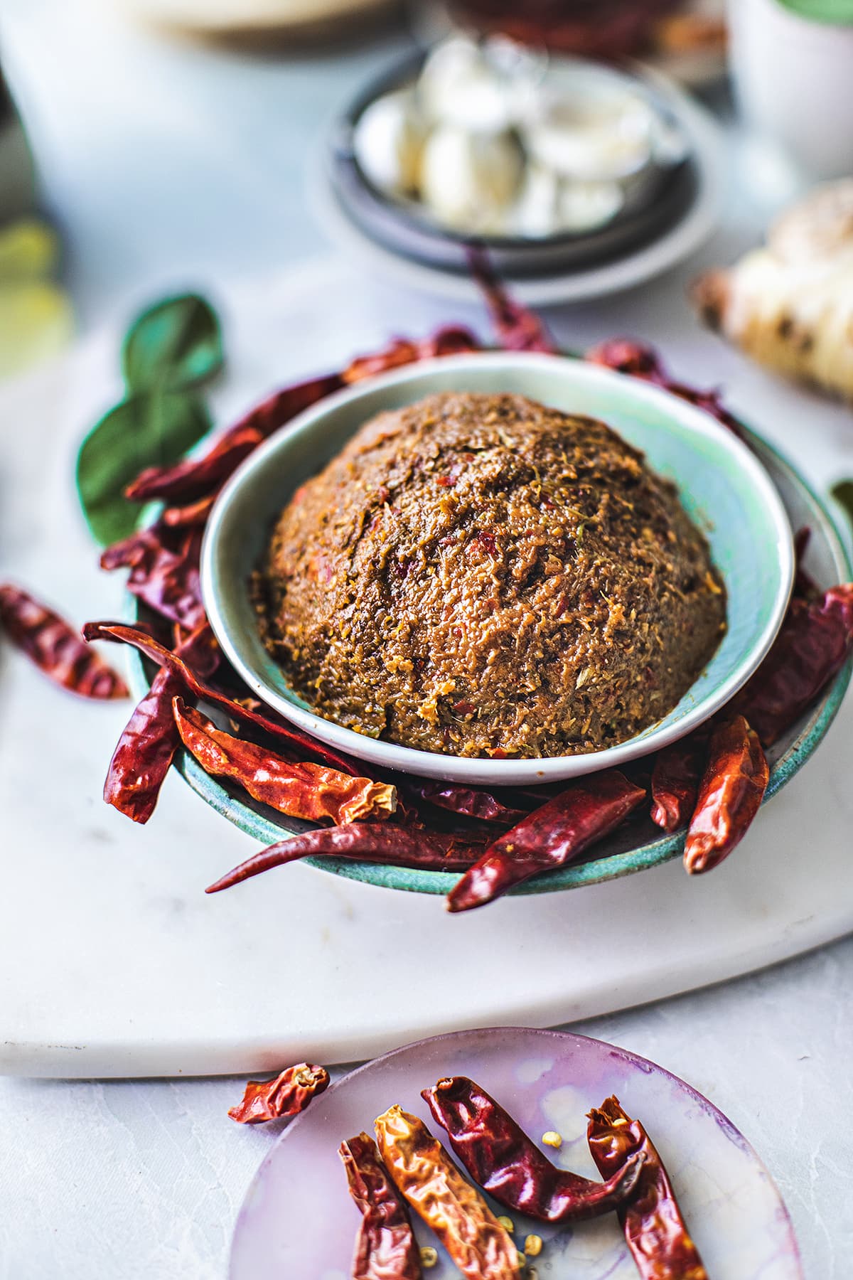 Prik Khing Curry paste in a green bowl with red chilis on the side. 