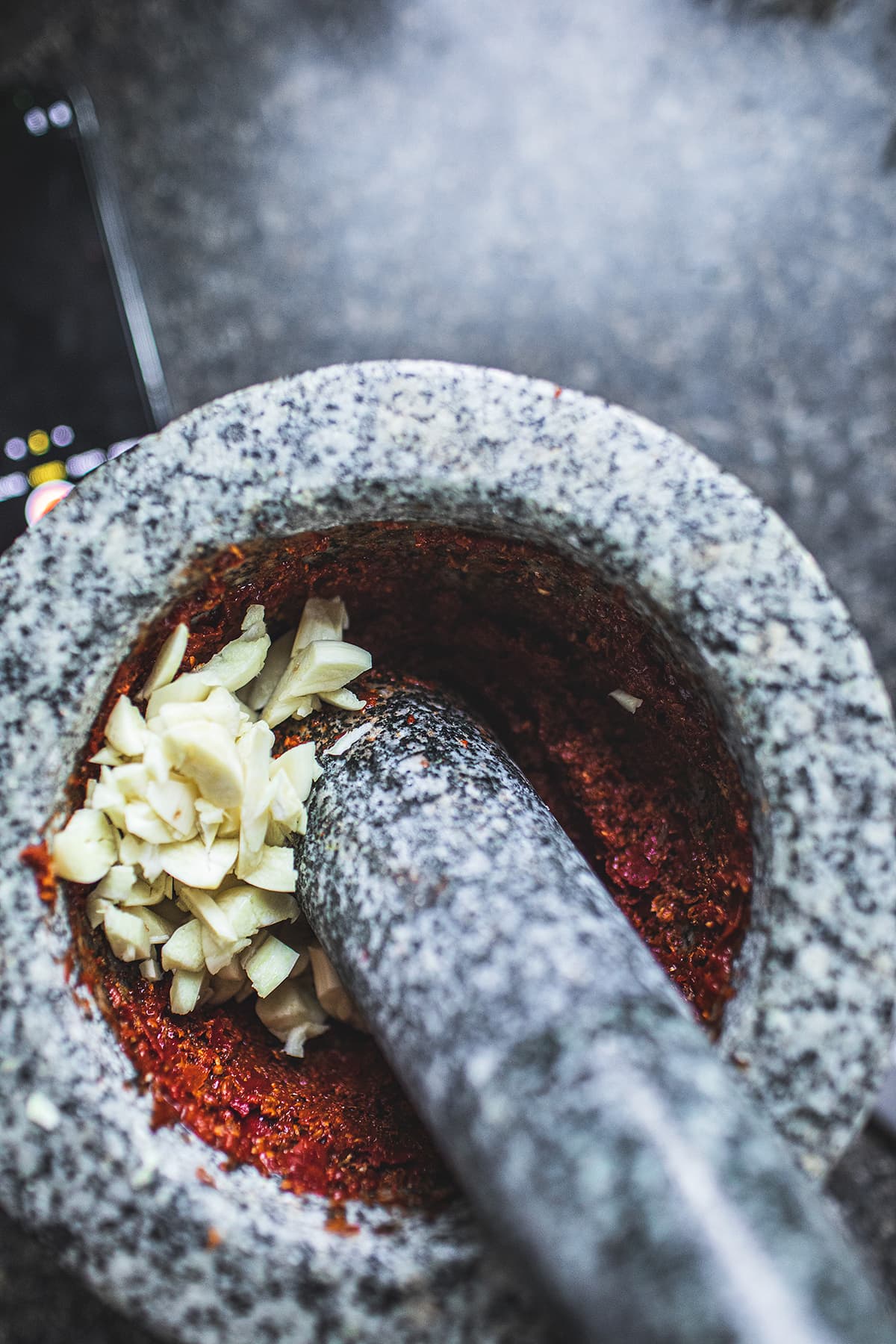 Prik Khing Thai curry paste in a mortar and pestle with chopped garlic.