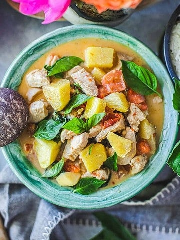 pineapple curry in a green bowl with basil leaves