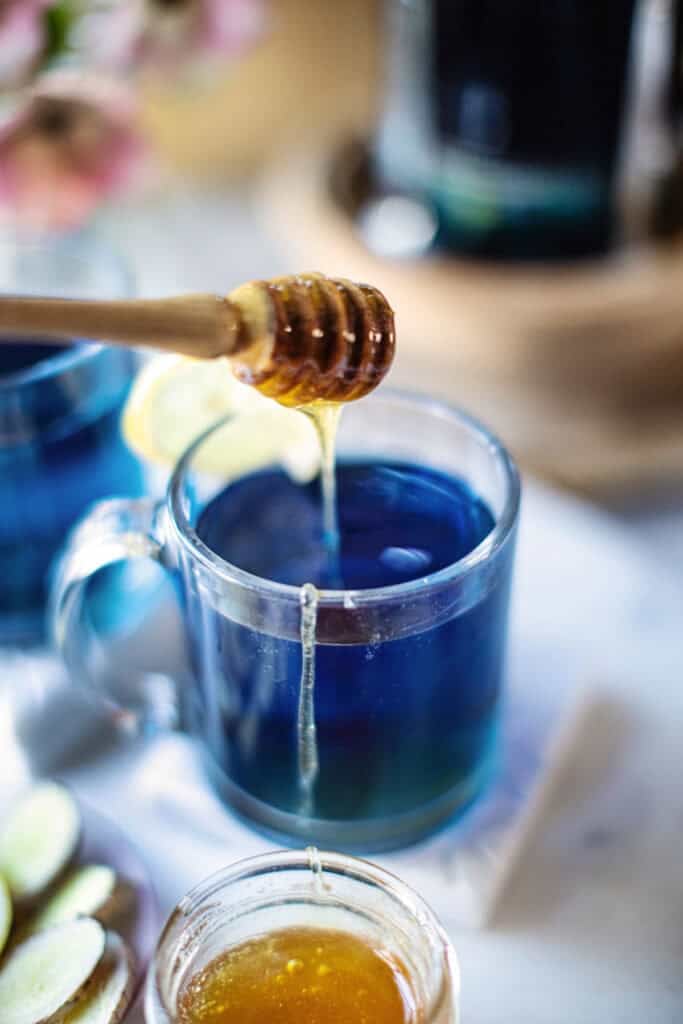 blue tea and honey in a clear glass.