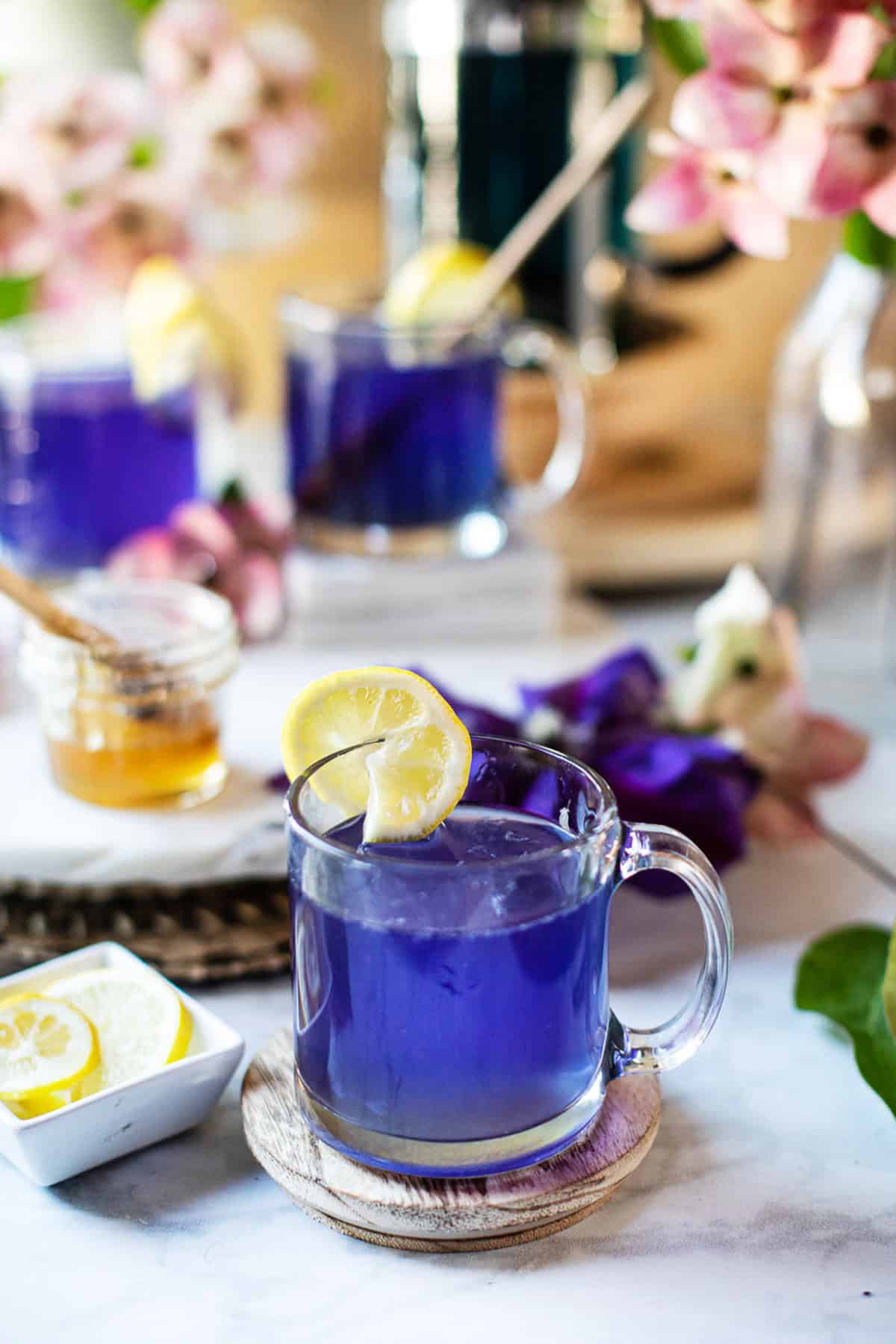 blue tea in a glass with lemon wedges.