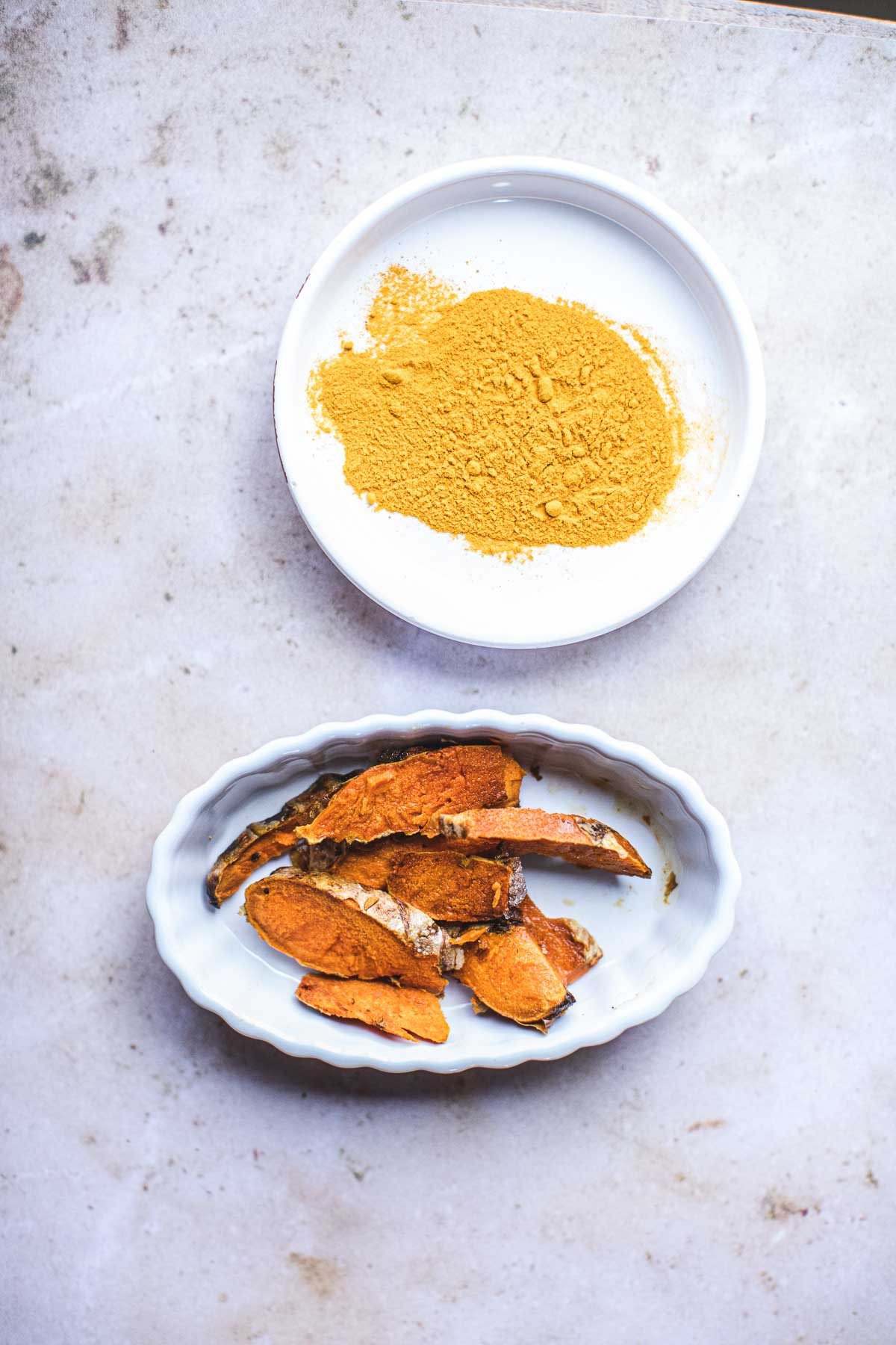 fresh turmeric next to powder turmeric in a bowl