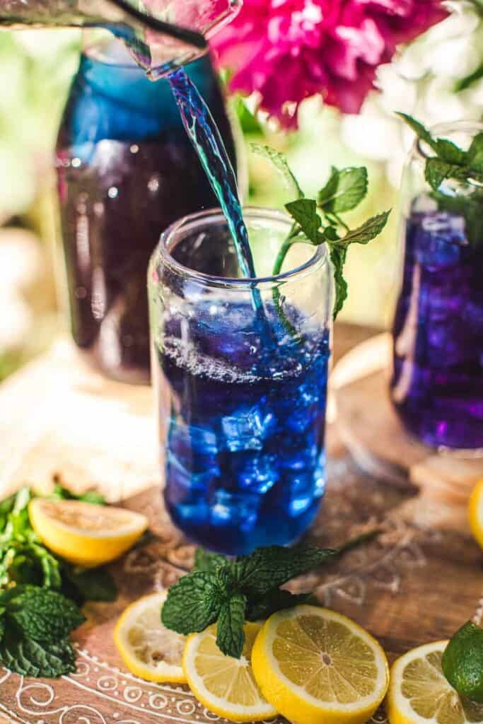 blue tea poured over a glass of ice