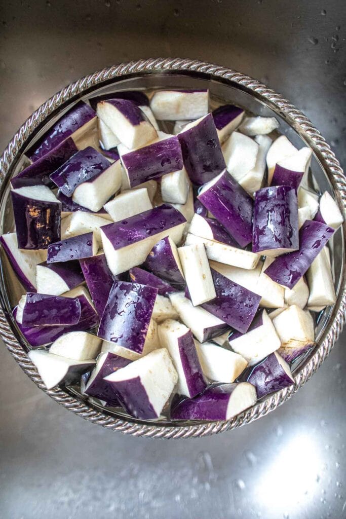 Sliced Chinese eggplants soaking in glass bowl.