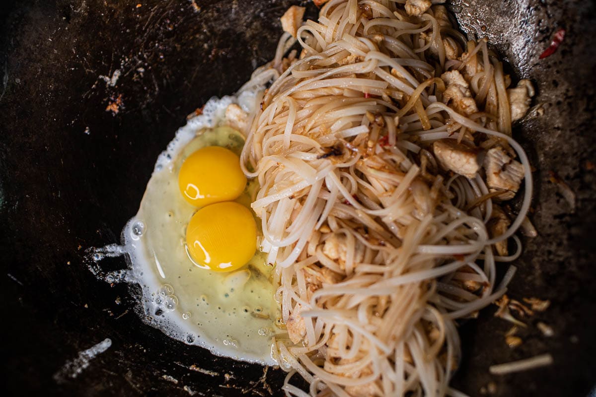 rice noodles and 2 eggs in a wok
