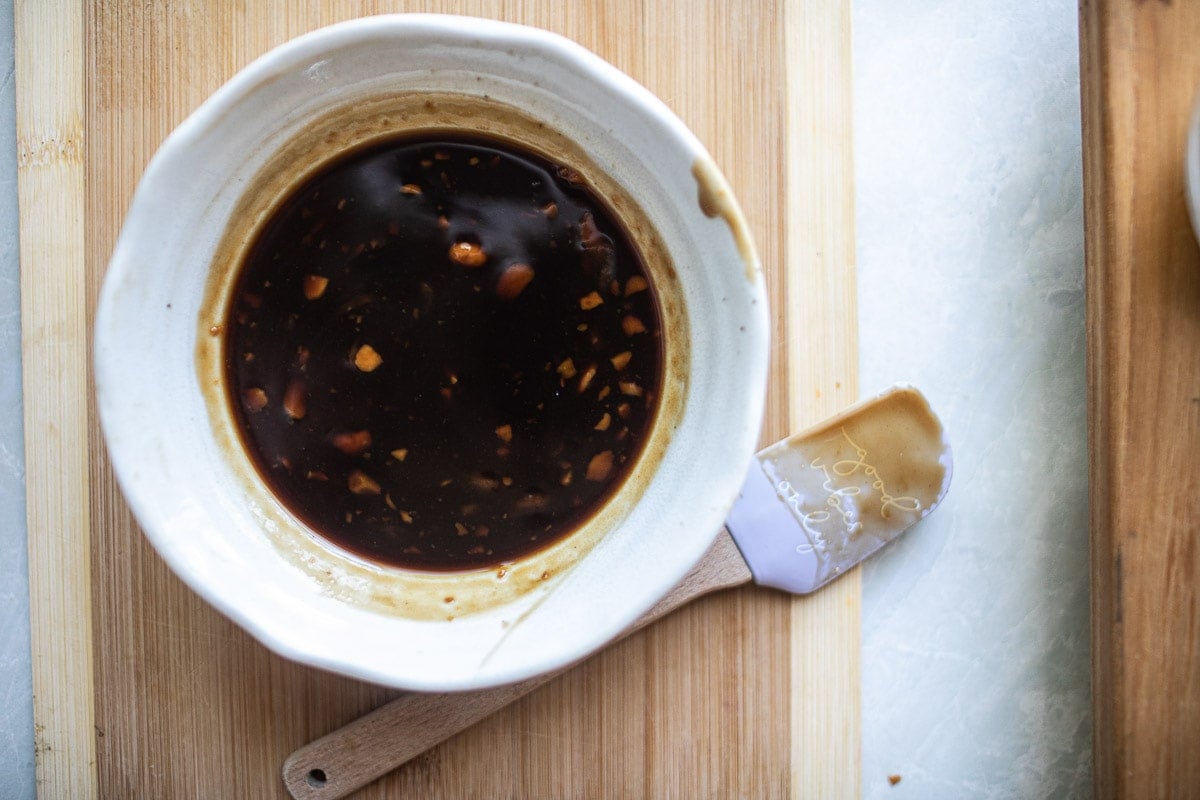 dark sauce in a white bowl on a cutting board