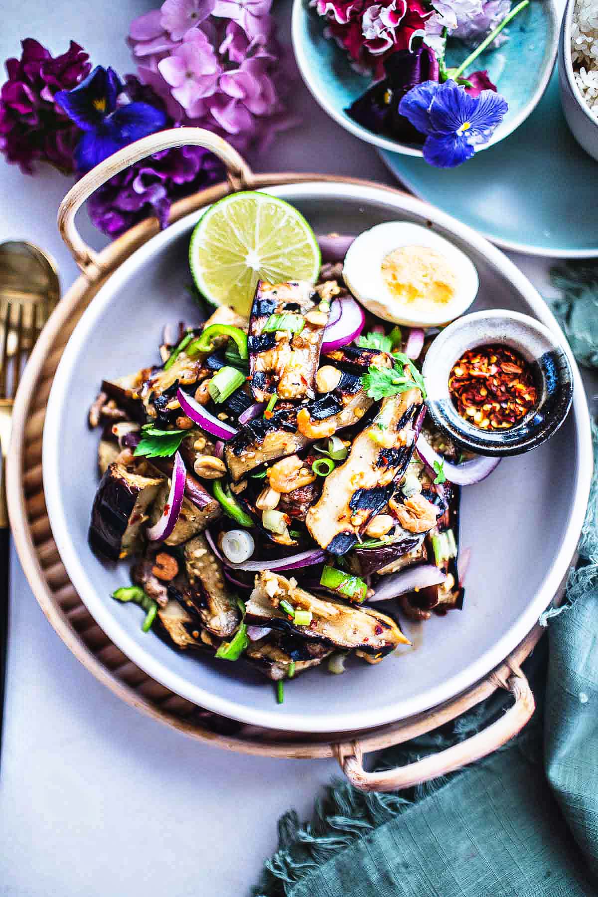 grilled Eggplant salad in a platter with lime, boiled egg and chili flakes garnish