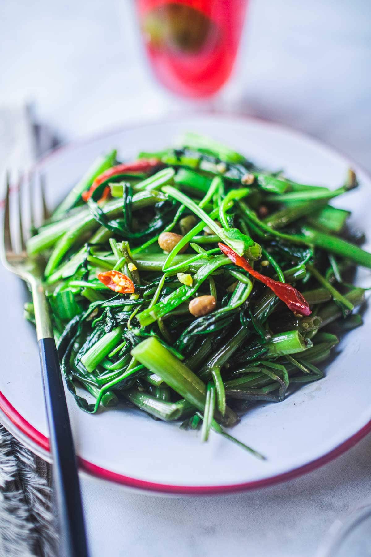 morning glory stir fried on a white plate with fork on the side