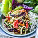 lao papaya salad in a plate with fresh veggies garnish by window
