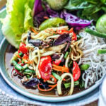 lao papaya salad in a plate with fresh veggies garnish by window