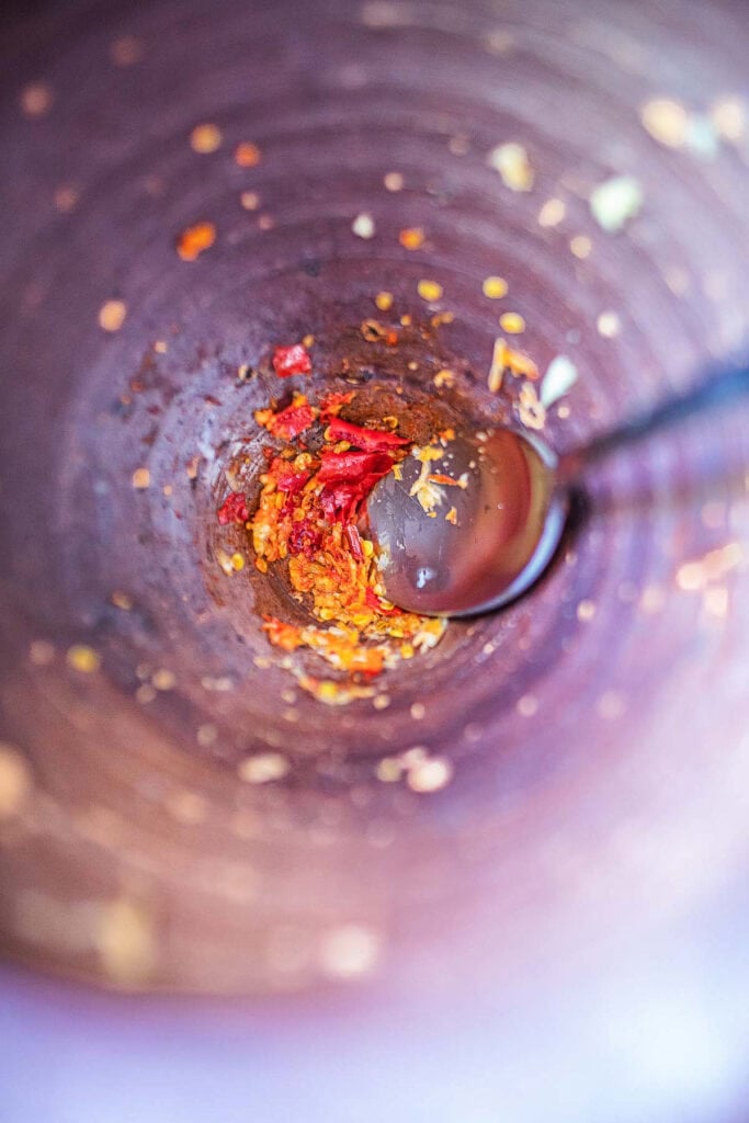 Thai chili and garlic pounded in mortar with a spoon in it.