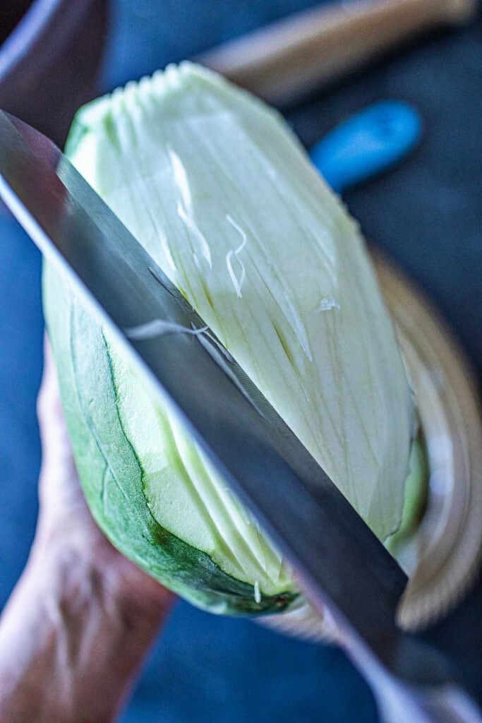 shredded peeled papaya with a knife