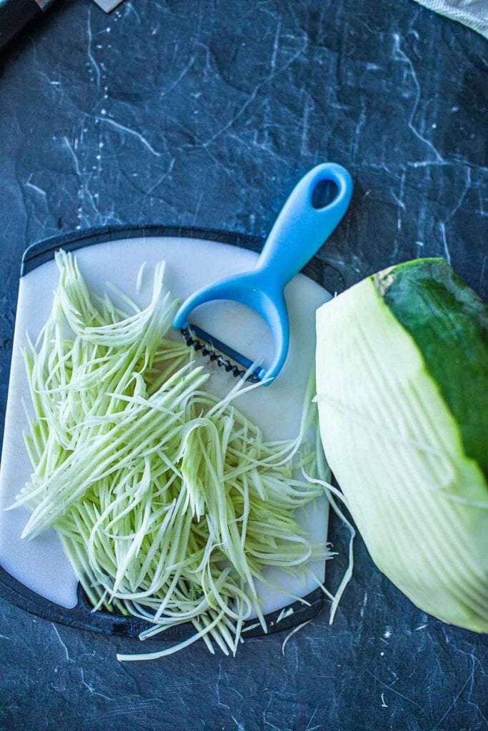 shredded peeled papaya with a peeler