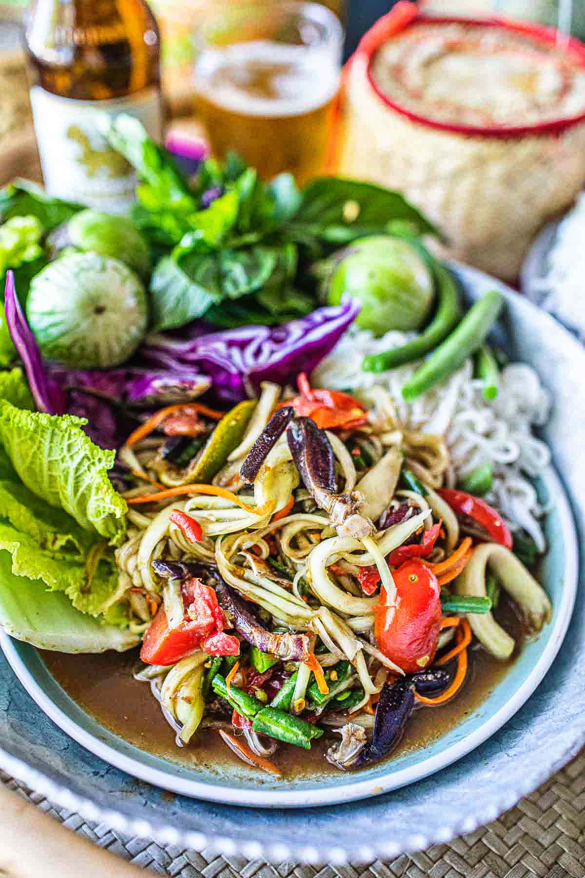lao papaya salad in a plate with fresh veggies garnish on a table