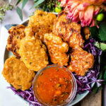 Thai corn fritters with dipping sauce on a cutting board
