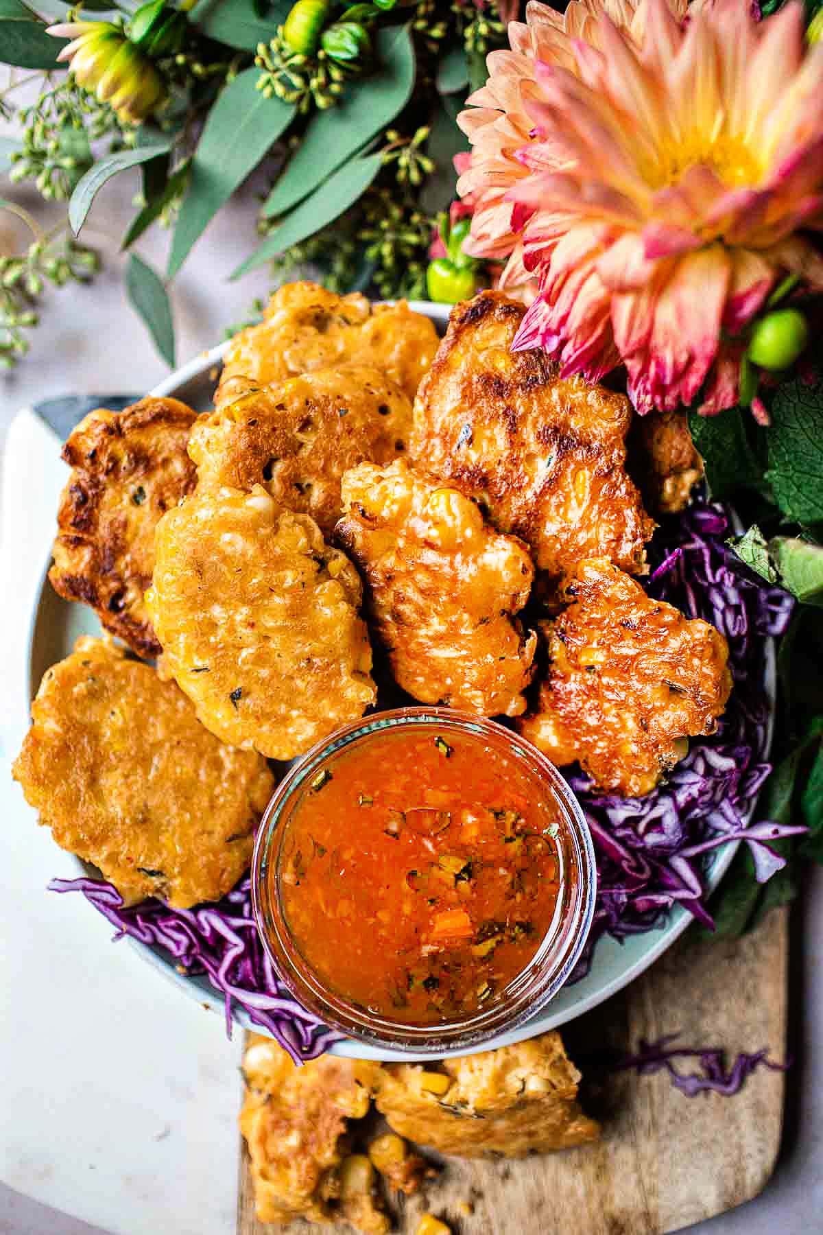 Thai corn fritters with dipping sauce on a cutting board