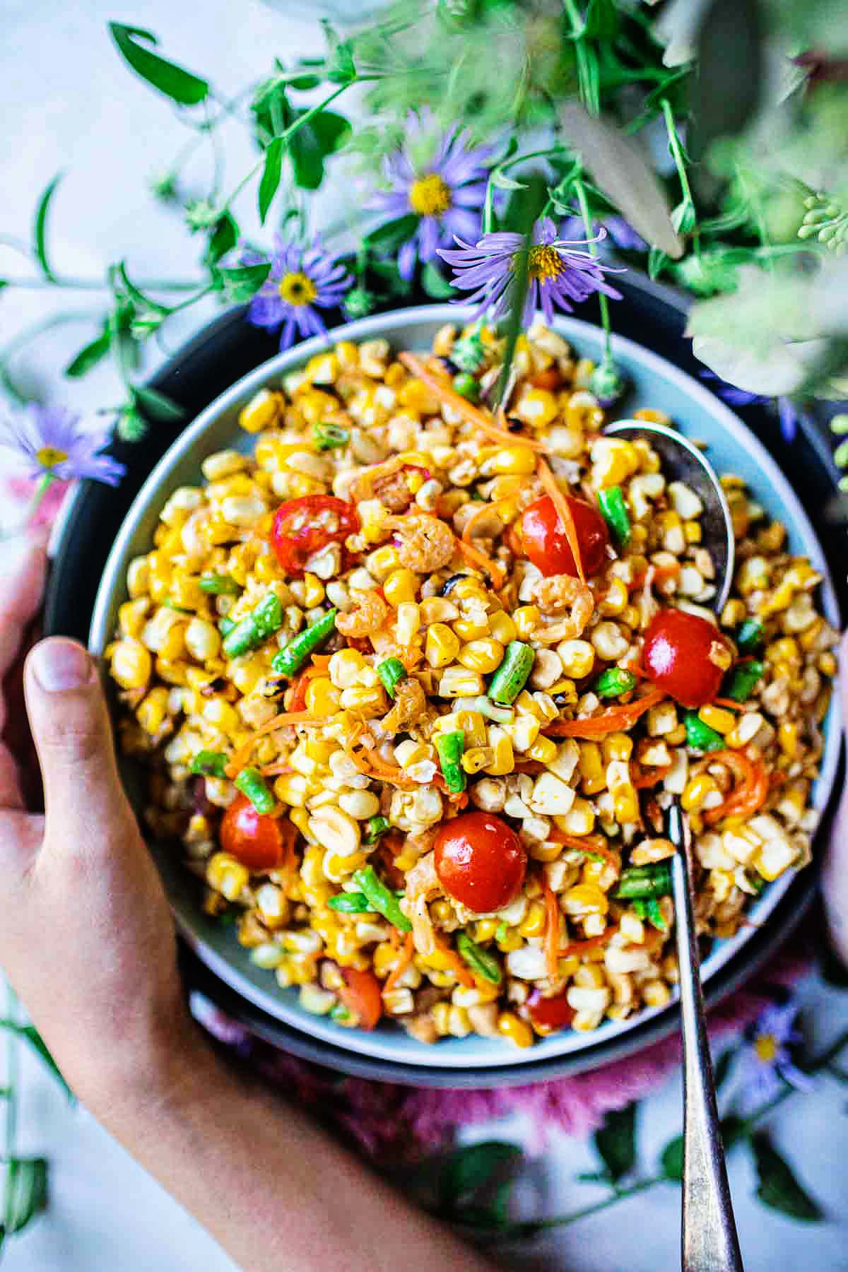 hand holding bowl of thai corn salad recipe