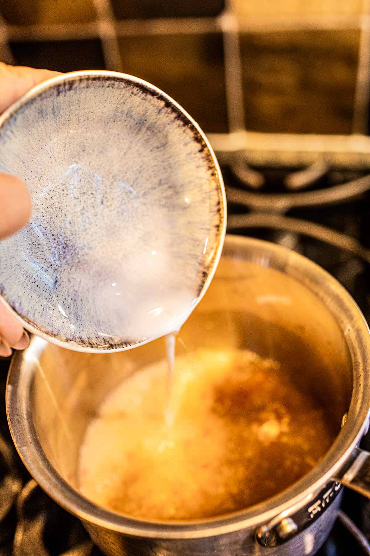 starch slurry pouring into thai chili dipping sauce in a pan