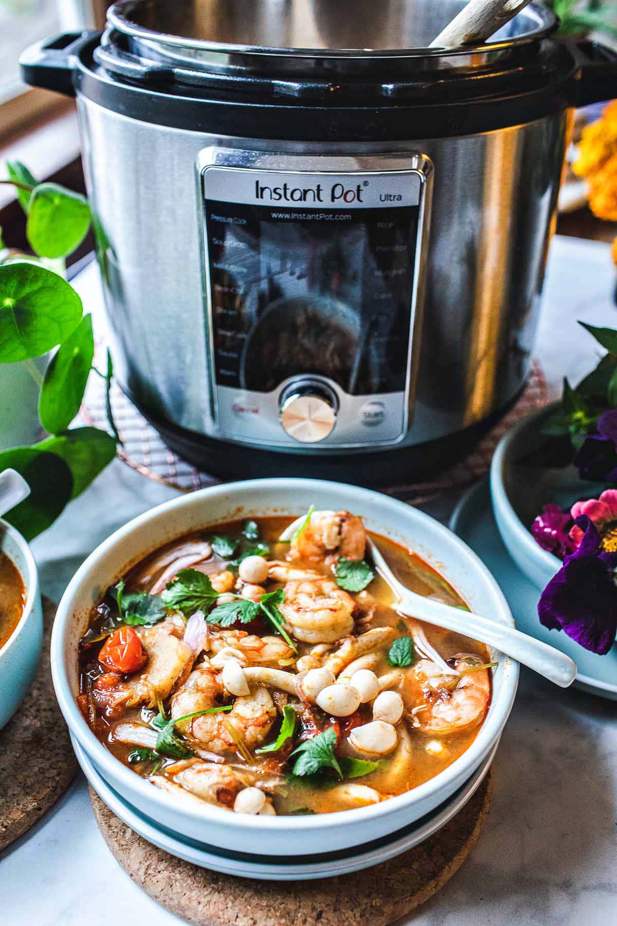 instant pot next a bowl of tom yum soup with shrimp