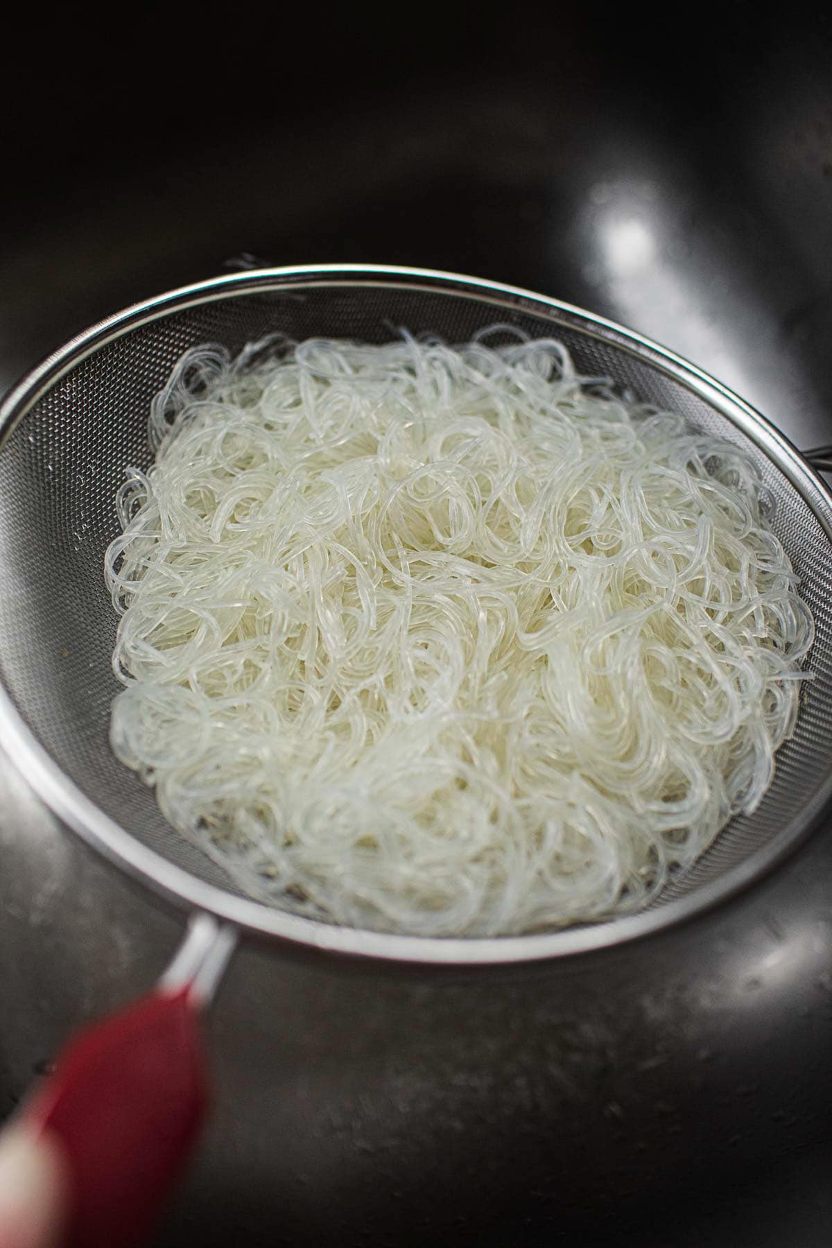 glass noodles in a strainer over sink