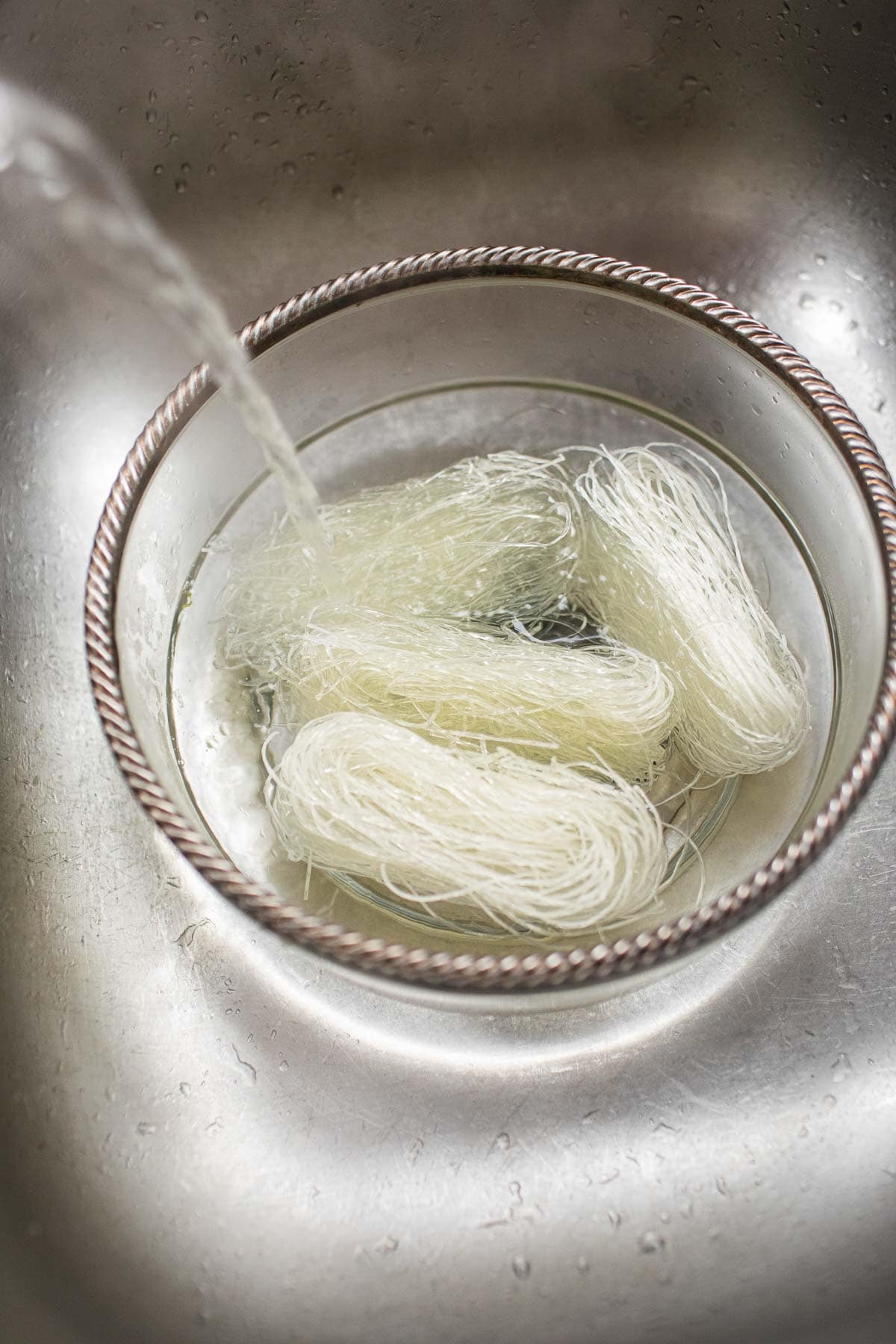 watering pouring over dry glass noodles over sink