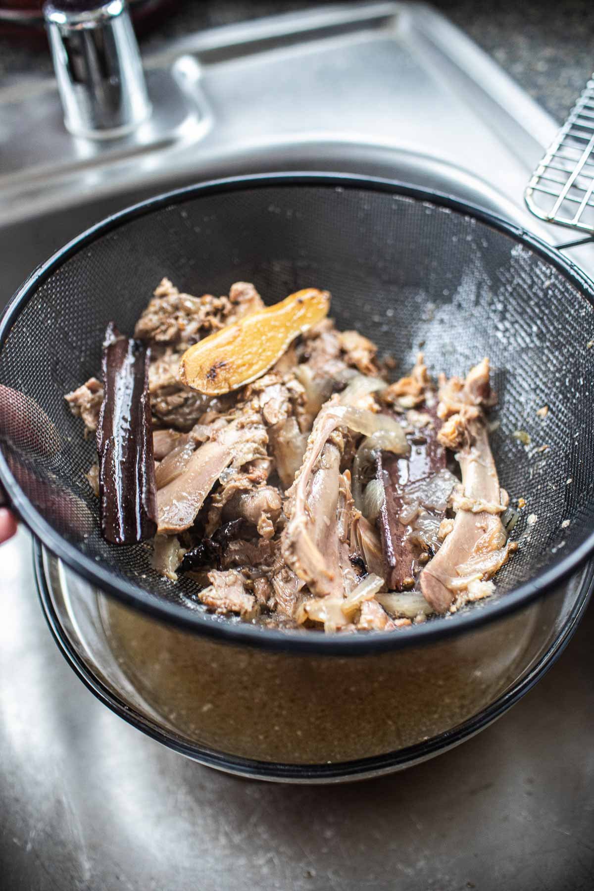 turkey bones and herbs in a strainer