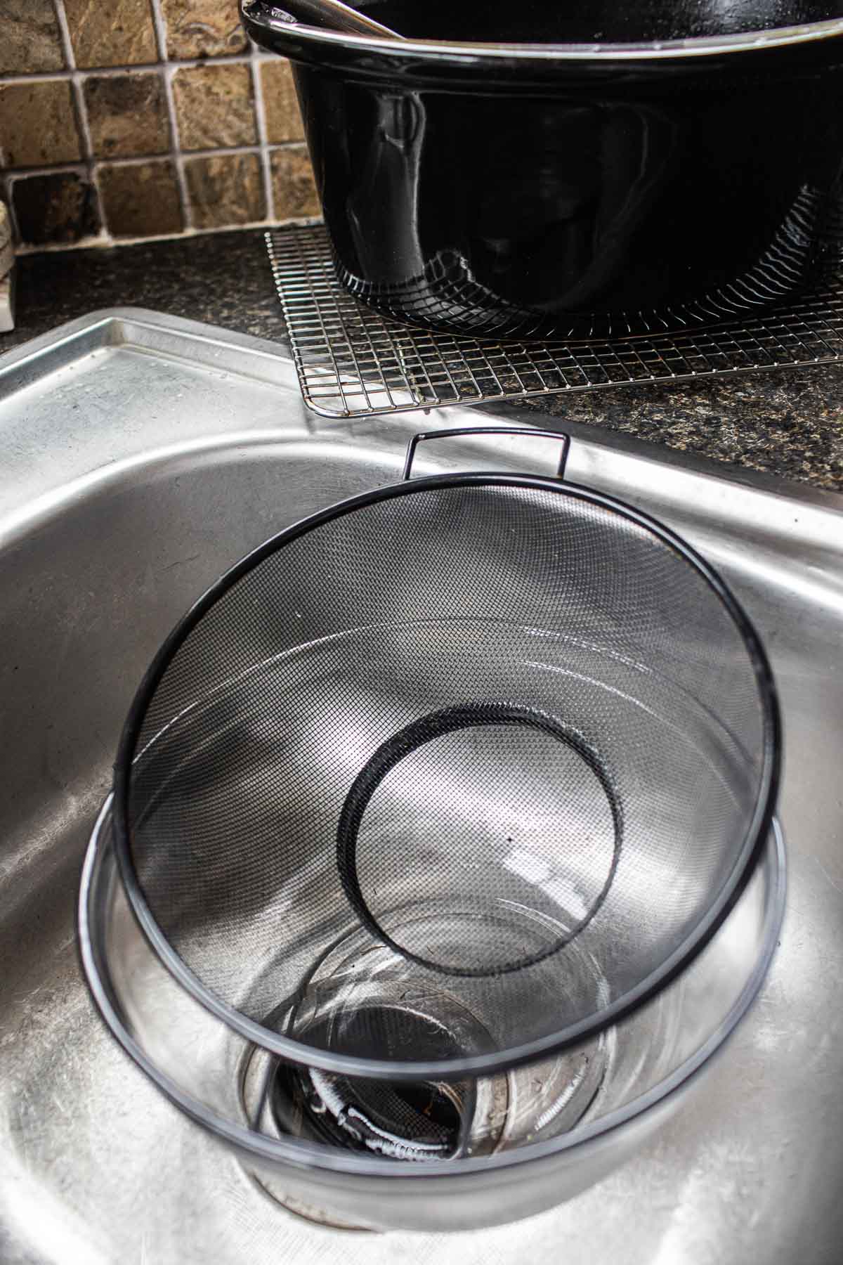 a strainer over glass bowl in a sink