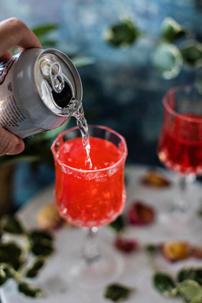 tonic pouring into a strawberry gin cocktail