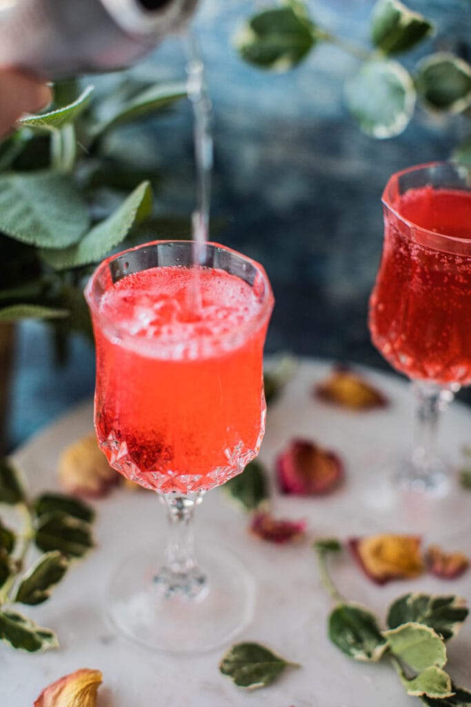 bubbly tonic pouring into a strawberry gin cocktail