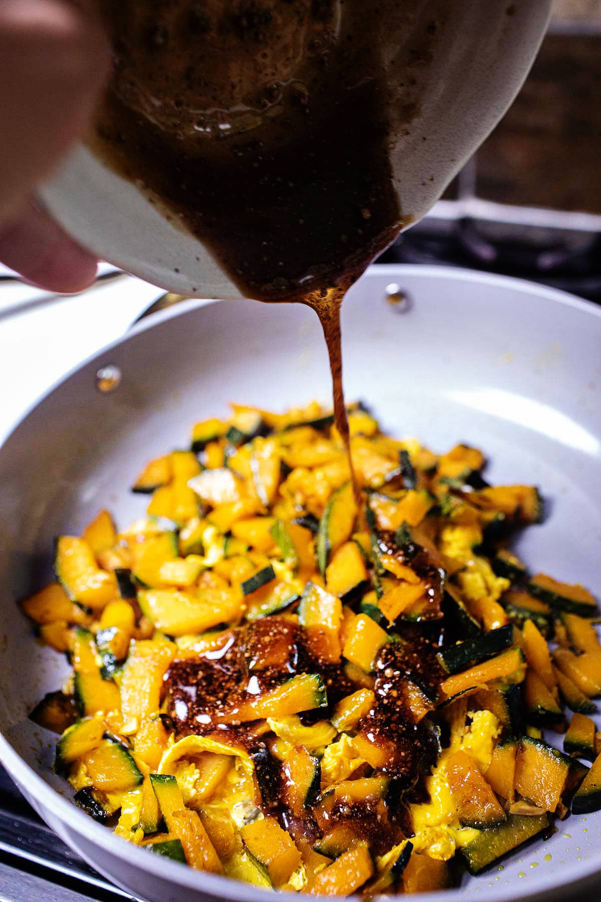 sauce pouring over kabocha in a pan