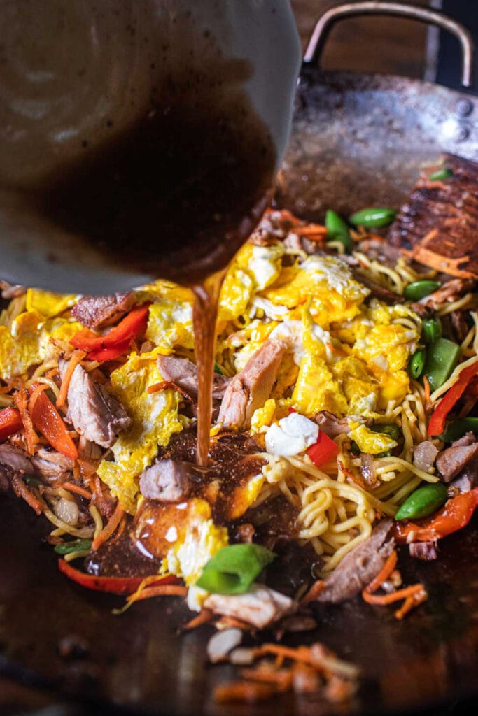 sauce pouring over wok of yakisoba stir fry